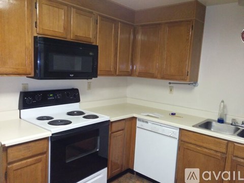 A kitchen with a black microwave above a stove and wooden cabinets.
