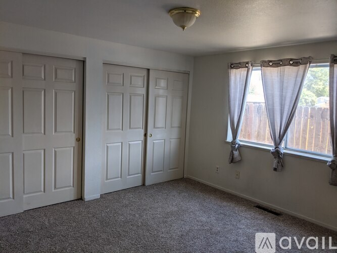 A room with two doors and a window with curtains.