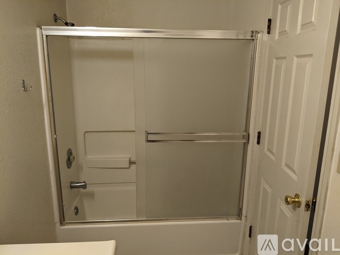 A white bathroom with a glass shower door and a white toilet.