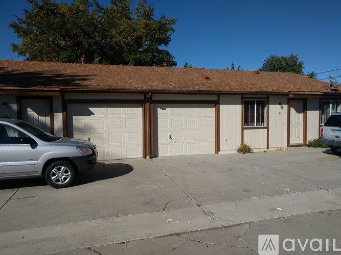 A silver car is parked in front of a two-car garage.