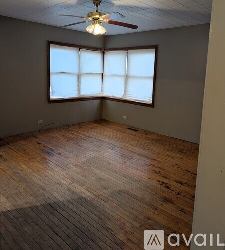 A room with wooden flooring and a ceiling fan.