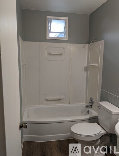 A bathroom with a toilet, tub, and window.