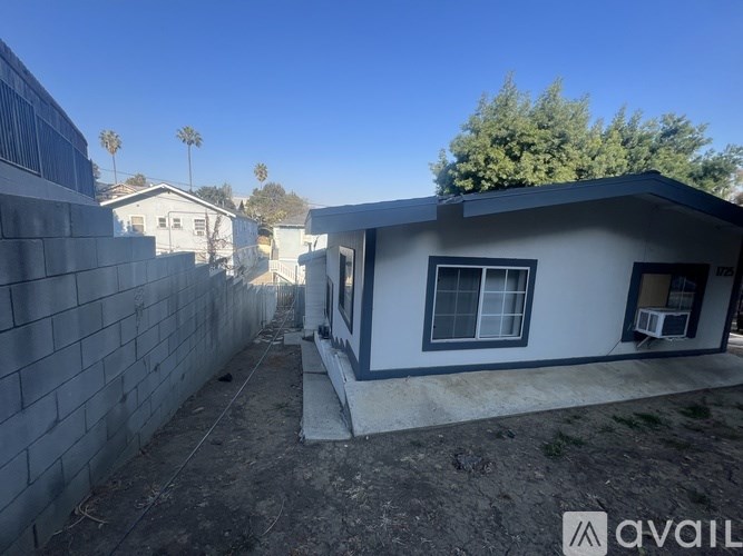 A house with a white exterior and a grey roof is shown with a clear blue sky in the background.