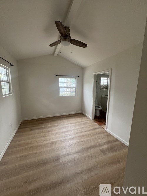 A room with a ceiling fan and wooden flooring.