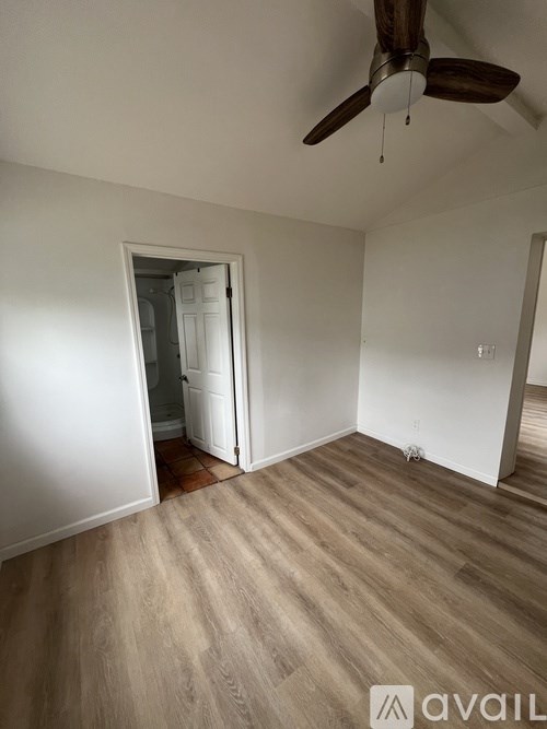 A room with a ceiling fan and a doorway leading to another room.