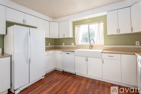 A kitchen with white cabinets and a white refrigerator.