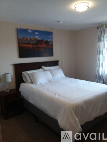 A bedroom with a large bed and a painting on the wall.