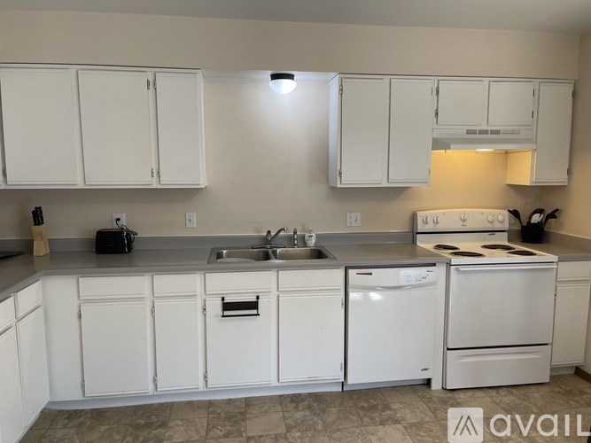 A kitchen with white cabinets and appliances.