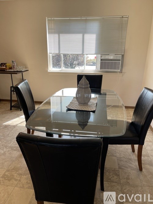 A glass dining table with four black chairs in a room.