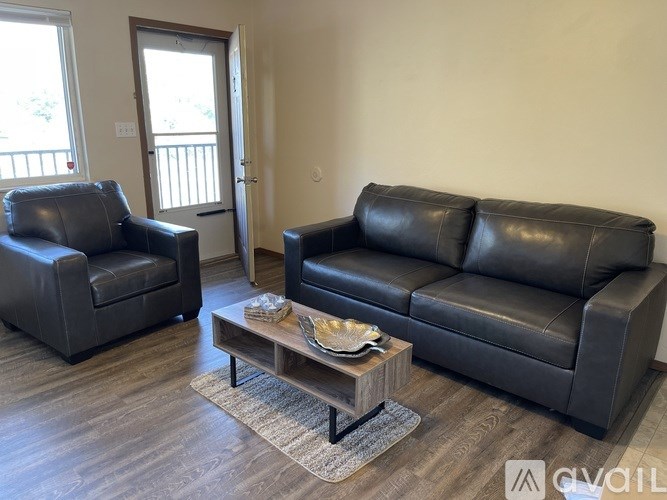 A black leather couch and chair in a room with a coffee table.