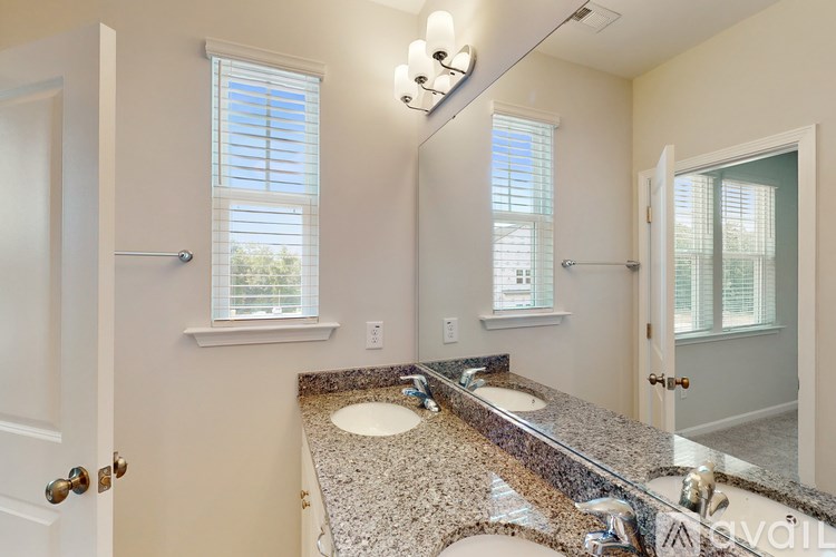 A bathroom with a granite countertop and double sinks.