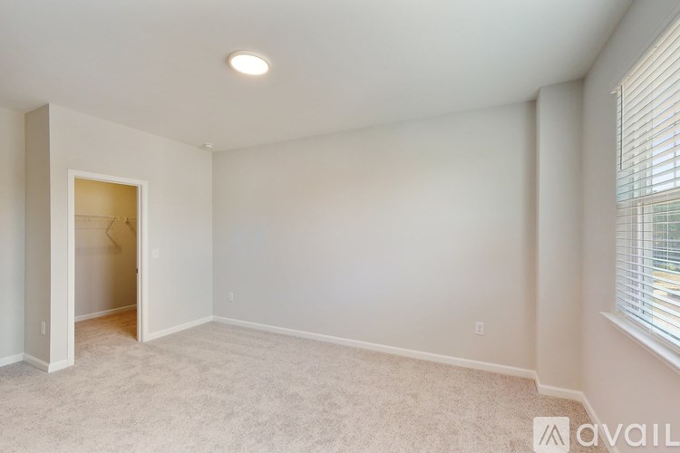 A room with a carpeted floor and a window with blinds.