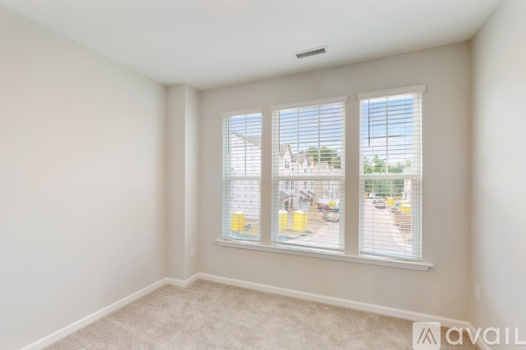 A room with a carpeted floor and a window with blinds.