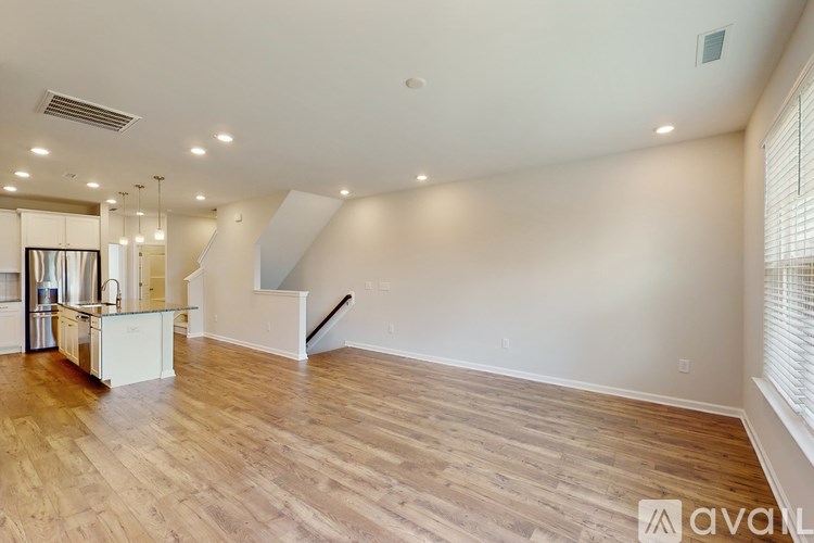 A spacious room with wooden flooring and a staircase leading to another level.