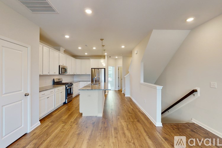 A spacious kitchen with wooden floors and white cabinetry.