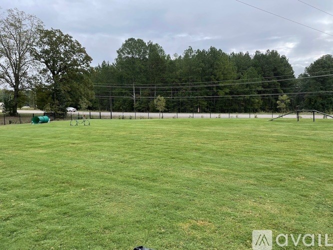 A grassy field with a fence and trees in the distance.