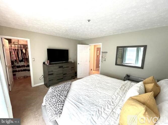 A bedroom with a bed, dresser, and television.