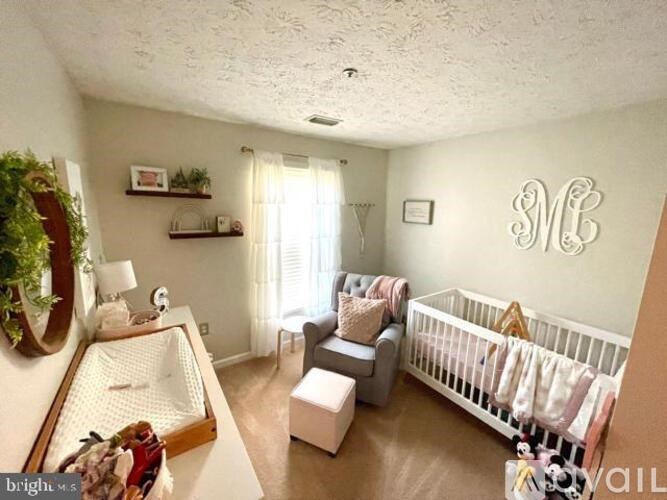 A baby nursery with a crib, chair, and a wall decoration.