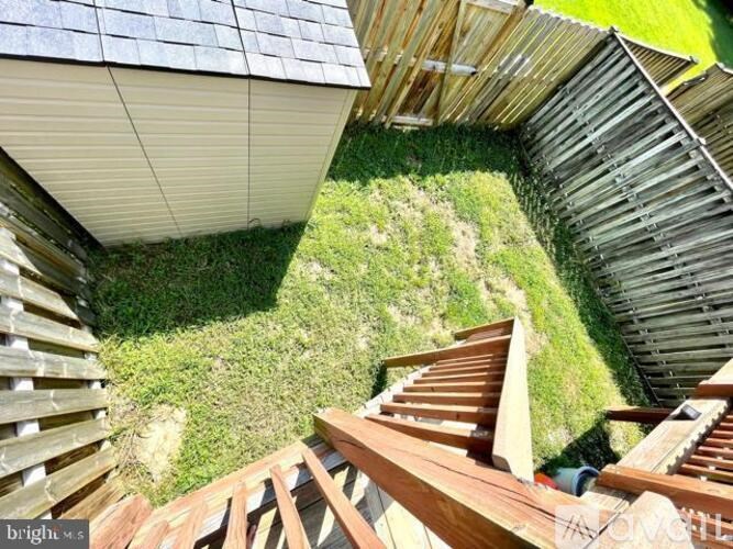 A wooden staircase leads up to a house with a grey roof.