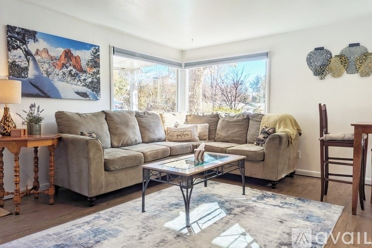 A living room with a couch, chair, and a painting on the wall.