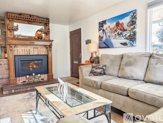 A living room with a fireplace and a painting of a mountain scene on the wall.