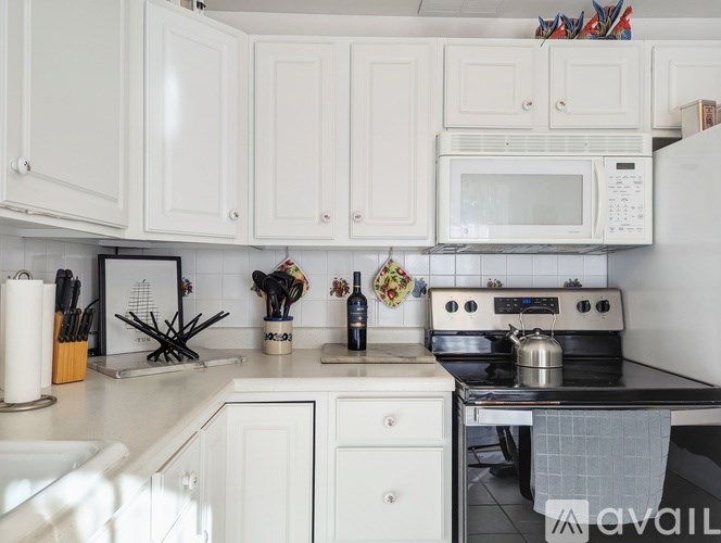 A kitchen with white cabinets and a white microwave above the stove.
