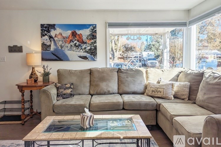 A living room with a large couch and a painting of a mountain scene on the wall.
