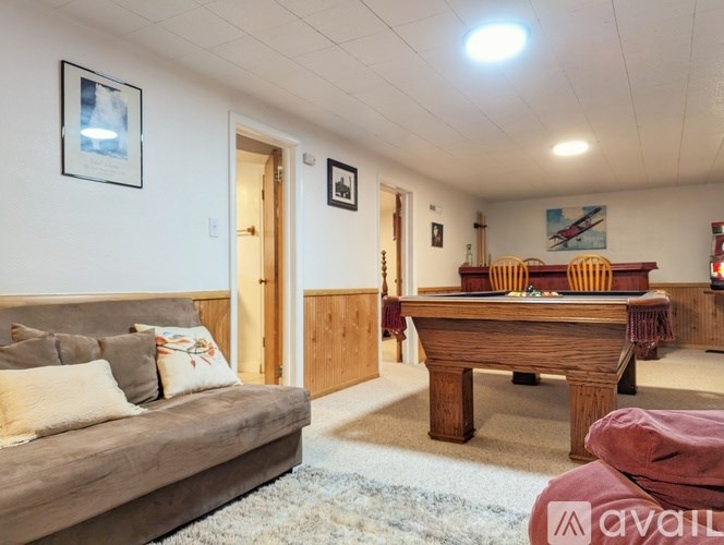 A living room with a couch, a pool table, and a billiard table.