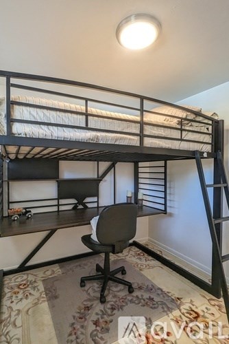 A black bunk bed with a chair and a rug in the room.