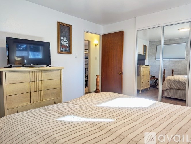 A bedroom with a bed, dresser, and a television.