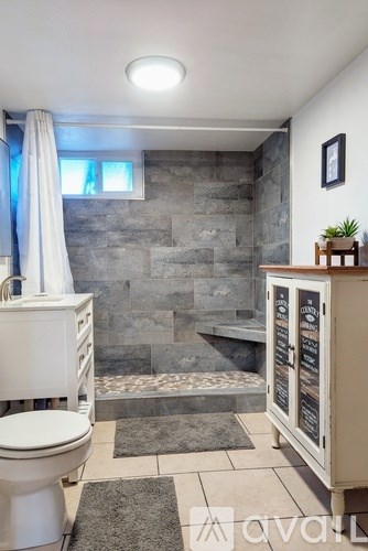 A bathroom with a toilet, sink, and a cabinet with a plant on top.