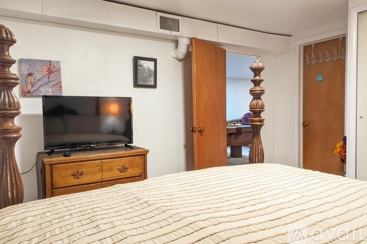 A bedroom with a bed, dresser, and television.