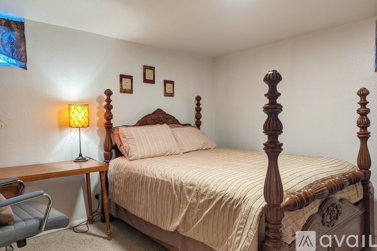 A bedroom with a bed, chair, and lamp.