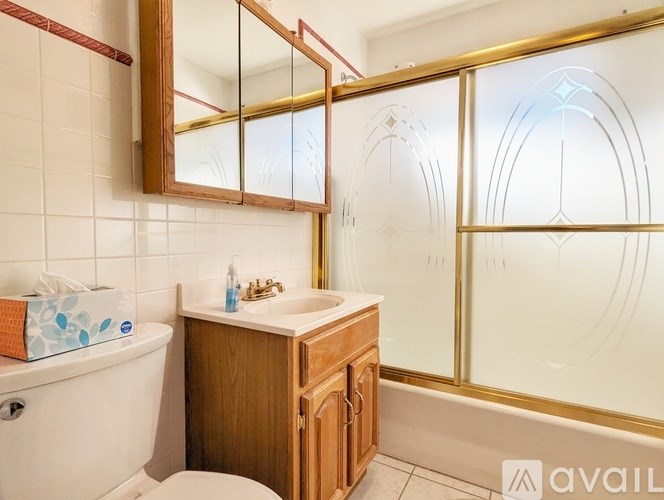A bathroom with a white bathtub, wooden vanity, and a large mirror.