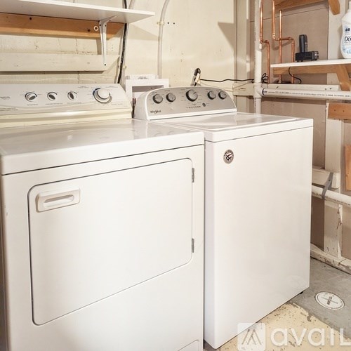A white dishwasher and oven are in a room with copper pipes.