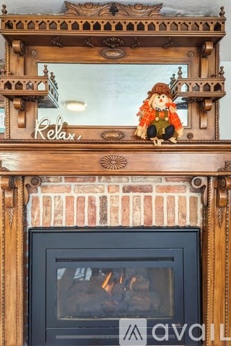 A wooden frame with a doll on top and a fireplace below.