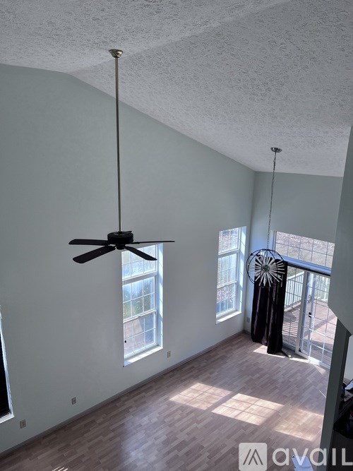 A room with a ceiling fan and a balcony with a railing.