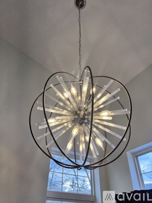 A chandelier with a circular glass shade and metal frame hangs from the ceiling.