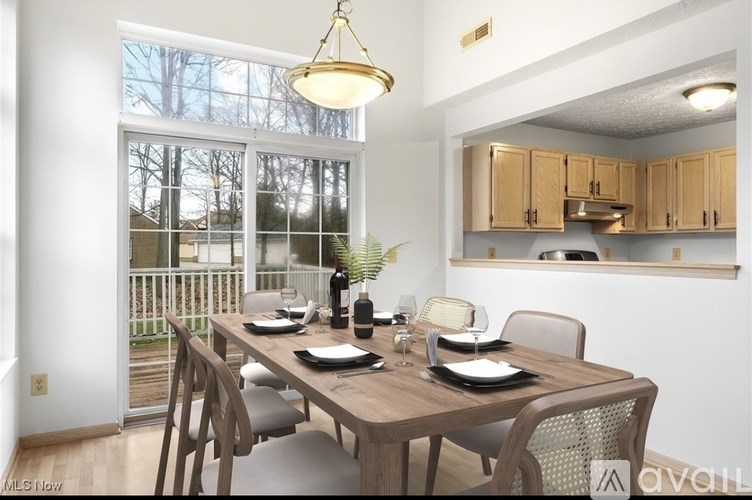 A dining room with a table set for two and a view of a deck outside.