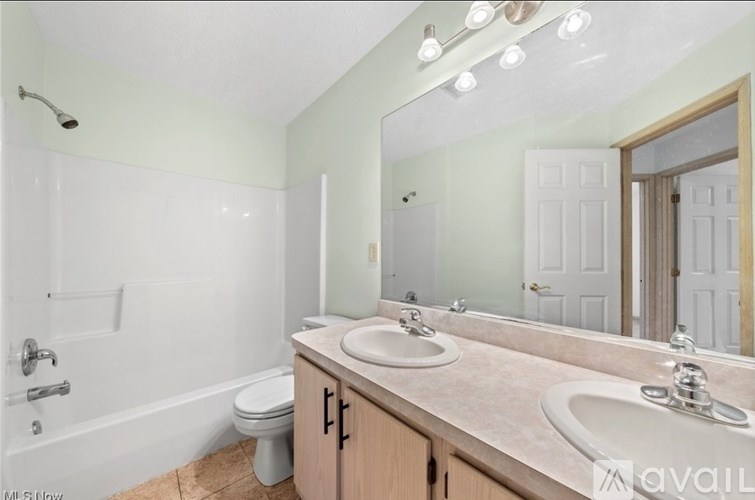A bathroom with a white tub, sink, and mirror.