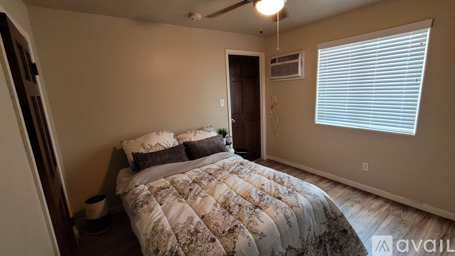 A bedroom with a bed, nightstand, and window.