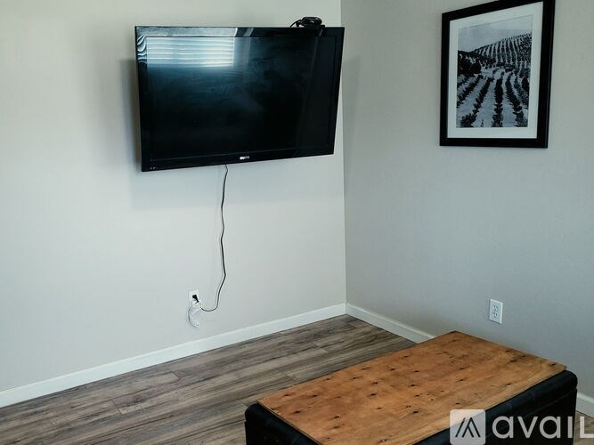 A black television is mounted on a wall above a wooden coffee table.