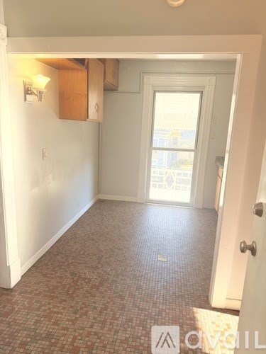 A hallway with a tiled floor and a door leading to a balcony.