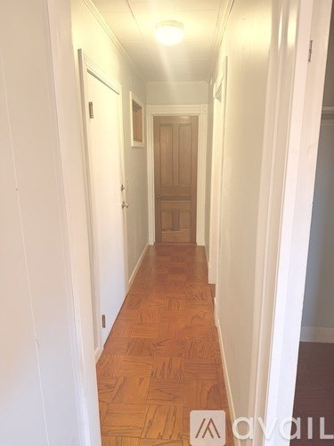 A long hallway with wood floors and white walls.