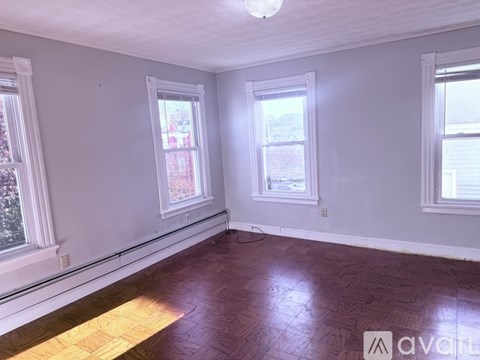 A room with wooden floors and three windows.