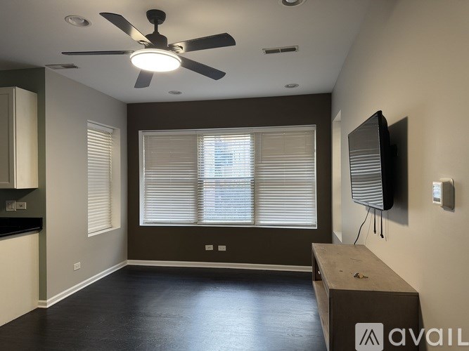 A room with a ceiling fan and a window with blinds.