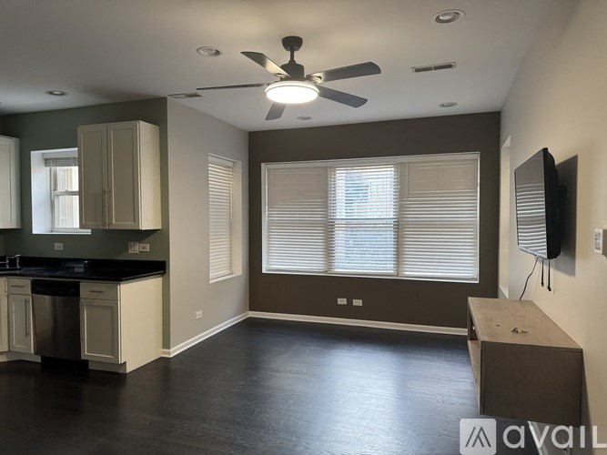 A kitchen with a black countertop and a ceiling fan.