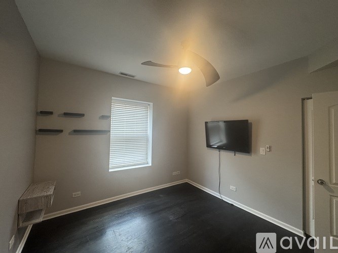 A room with a flat screen TV mounted on the wall and a window with blinds.