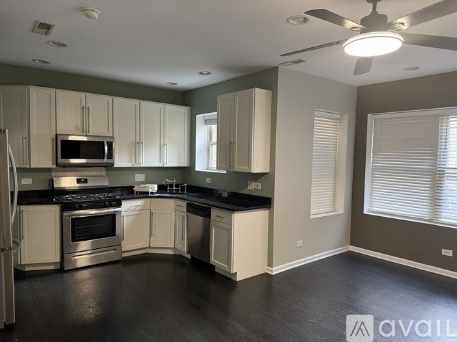 A kitchen with white cabinets and black countertops is available for rent.