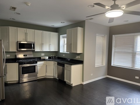 A kitchen with white cabinets and black countertops is available for rent.